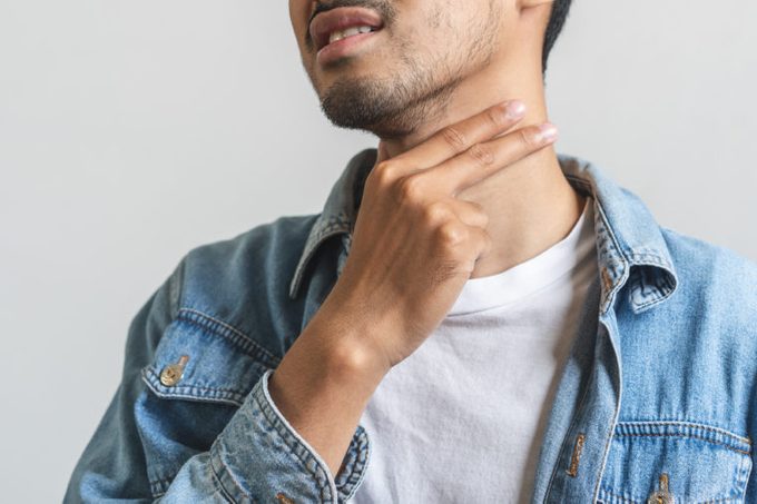 Close up asian man touching his neck and having sore throat.