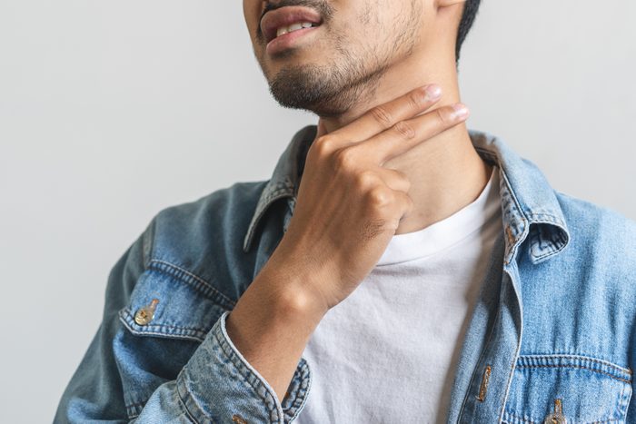 Close-up aziatische man die zijn nek aanraakt en keelpijn heeft.
