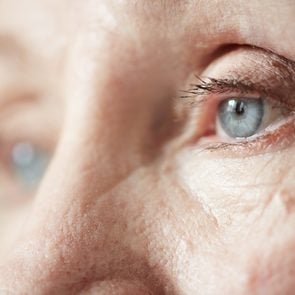 Sad blue-grey eyes of elderly woman looking to the side, extreme close-up shot