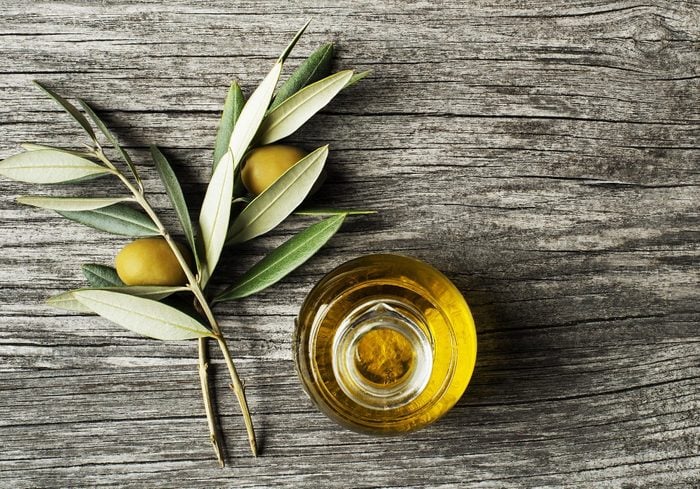 Olive oil and olive branch on wooden table