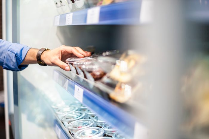 close up of man's hand taking food from shelf at the store