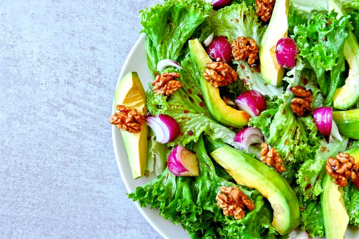 Useful salad on a plate. Salad with avocado and greens. Vegan salad with walnuts.