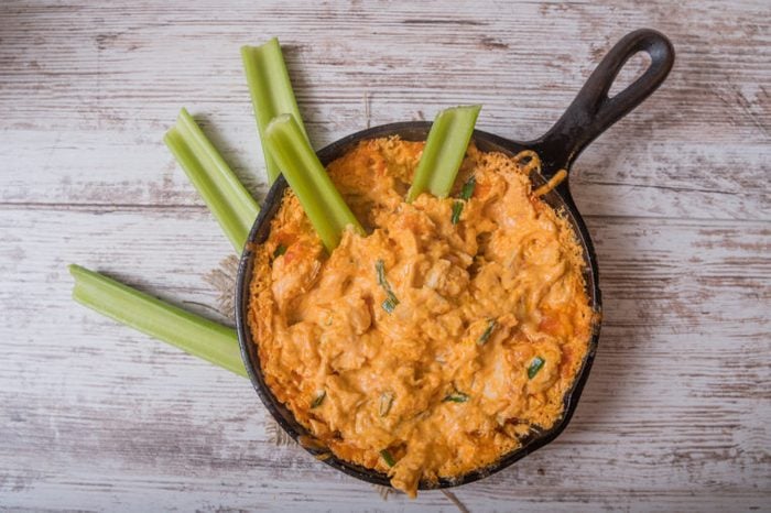 Flat lay of a skillet with spicy buffalo chicken cheese dip with celery