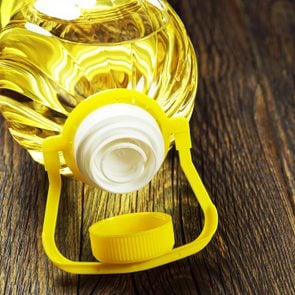 Vegetable oil in plastic bottle on old wooden table closeup
