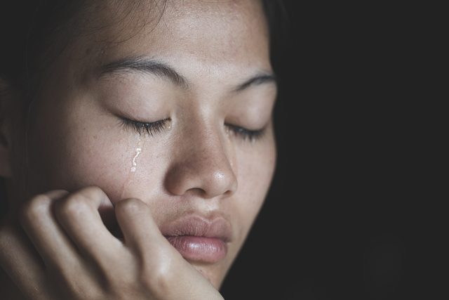woman crying tears eyes closed dark