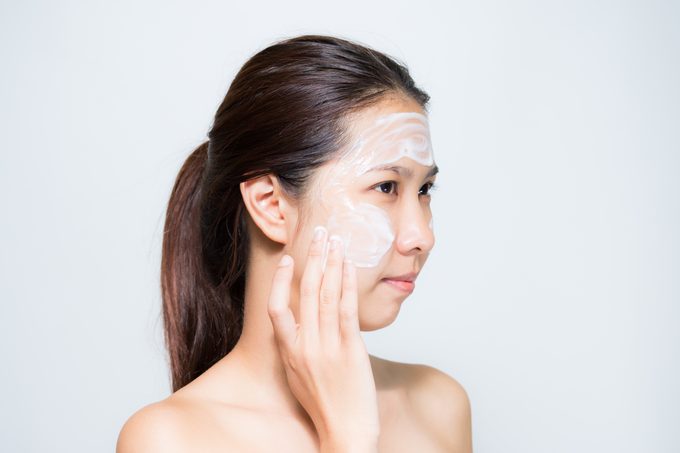woman applying lotion or mask to face