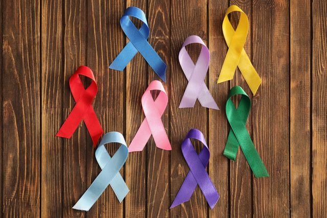 Different ribbons on wooden background. Cancer awareness concept