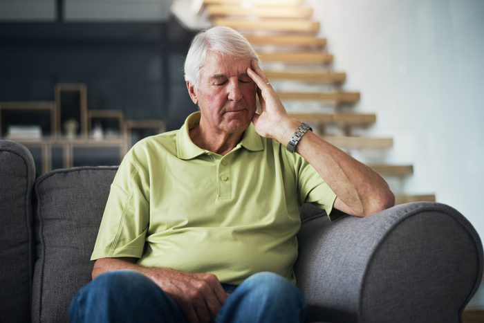 man feeling unwell on couch at home