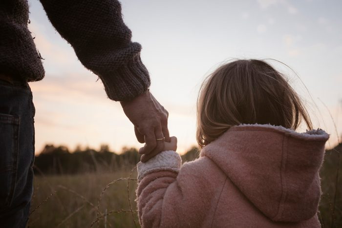 Father and daughter holding hands in field