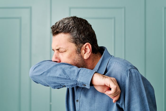 man coughing into arm