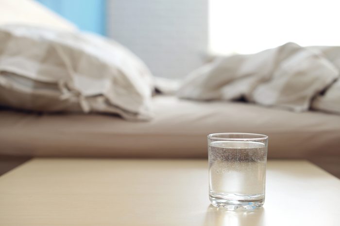 glass of water on table next to bed