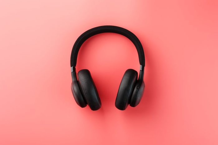 Wireless black headphones on a pink background. On-ear headphones for playing games and listening to music tracks.