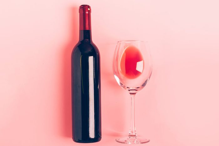 A bottle of wine an empty glass of a bunch of red grapes on a gentle pink background. Flat layout top view. Copy space. Minimalism. Horizontal frame; Shutterstock ID 1409701445; Job (TFH, TOH, RD, BNB, CWM, CM): -