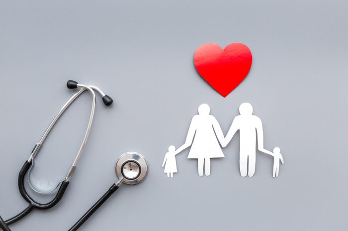 Take out health insurance for family. Stethoscope, paper heart and silhouette of family on grey background top view