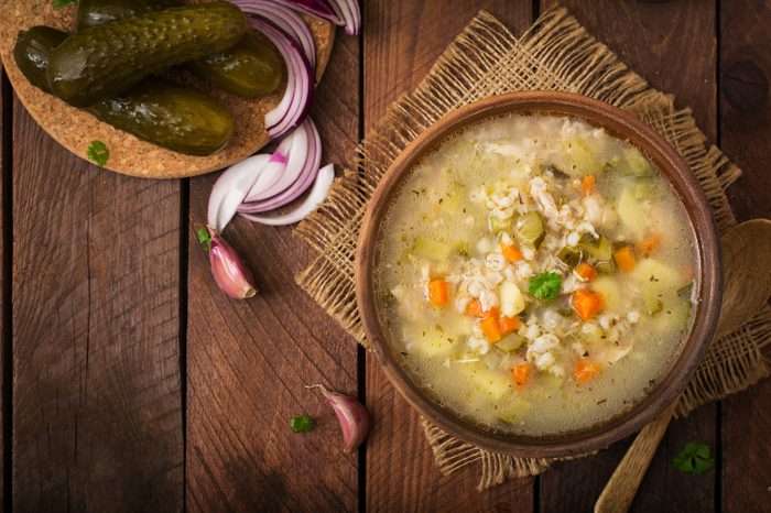 Soup with pickled cucumbers and pearl barley - rassolnik on a wooden background. Top view. 