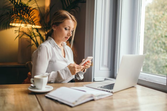 woman working and procrastinating on cell phone
