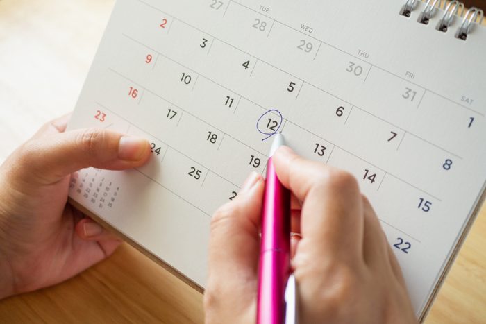 Hands circling a date on a calendar