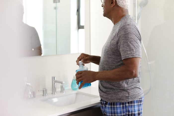 man using mouthwash in bathroom