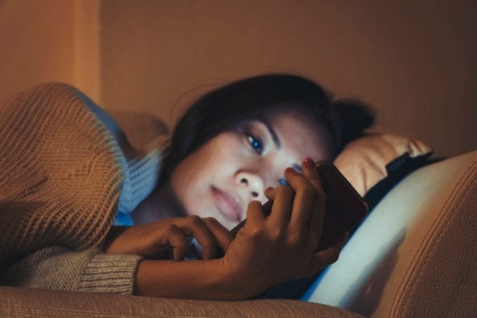 woman looking at phone in bed at night