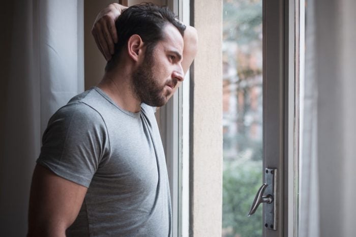 man looking out of window of home