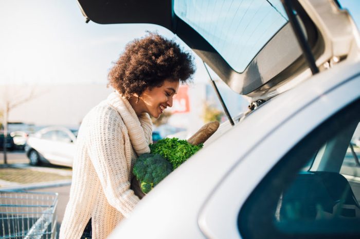 woman putting groceries into the trunk of car