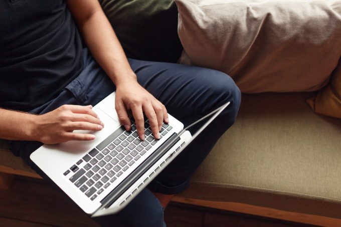 man using laptop at home on couch
