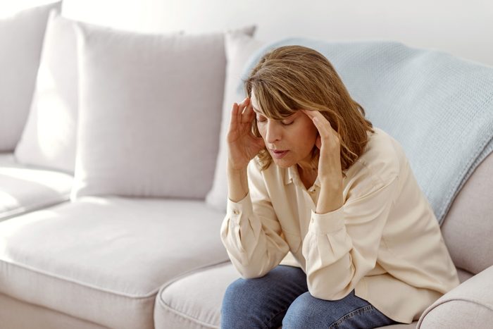 woman sitting on couch with headache pain