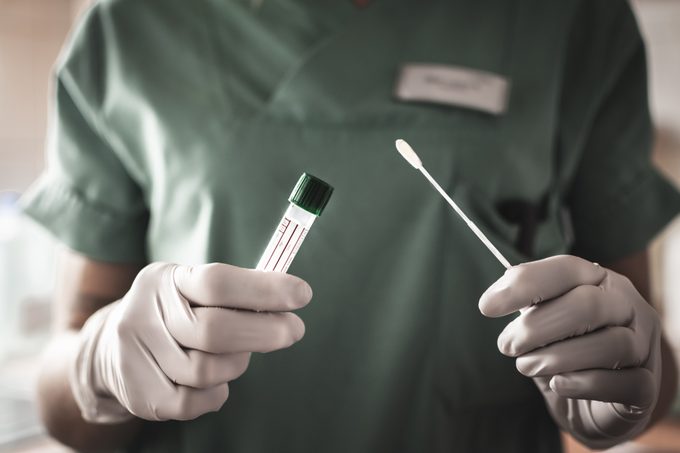 nurse or doctor holding test swab and test tube for coronavirus testing