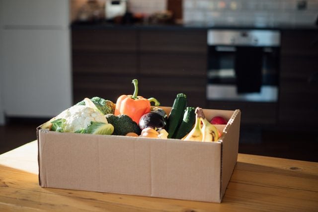fresh groceries in cardboard box on kitchen table
