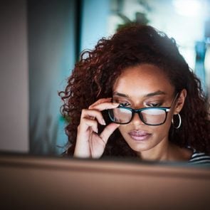 woman wearing anti blue light glasses working on computer late at night