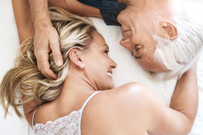 older couple laying down in bed together showing affection