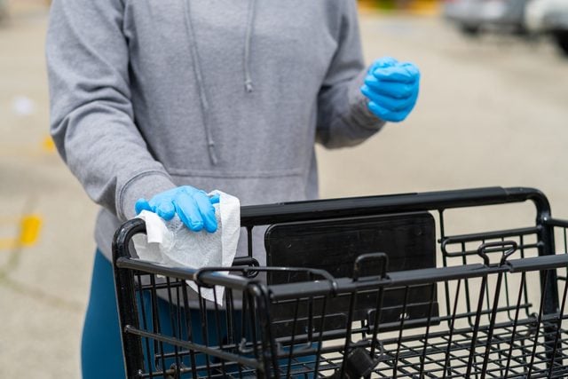 customer wearing gloves and wiping down shopping cart