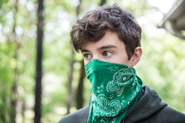 Teenage boy wearing bandana over face
