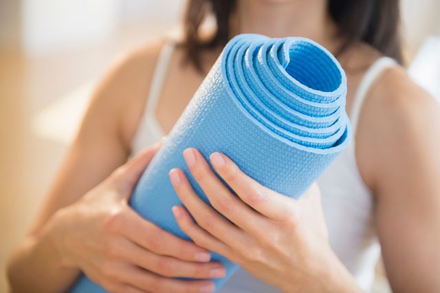 close up of woman holding a blue yoga mat