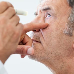 eye doctor examining elderly man's eyes
