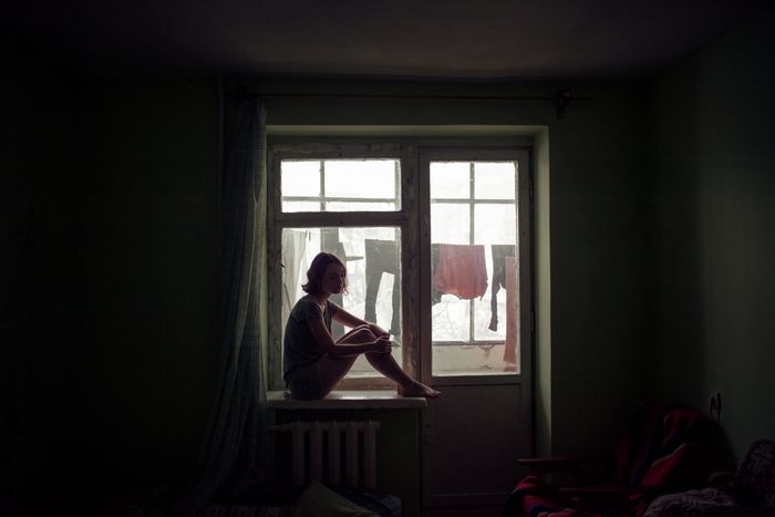 silhouette of woman sitting on window sill