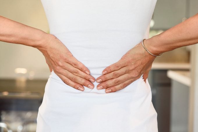 cropped rear shot of woman's hands on lower back