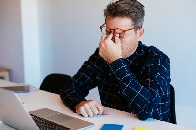 stressed man sitting at desk trying to work
