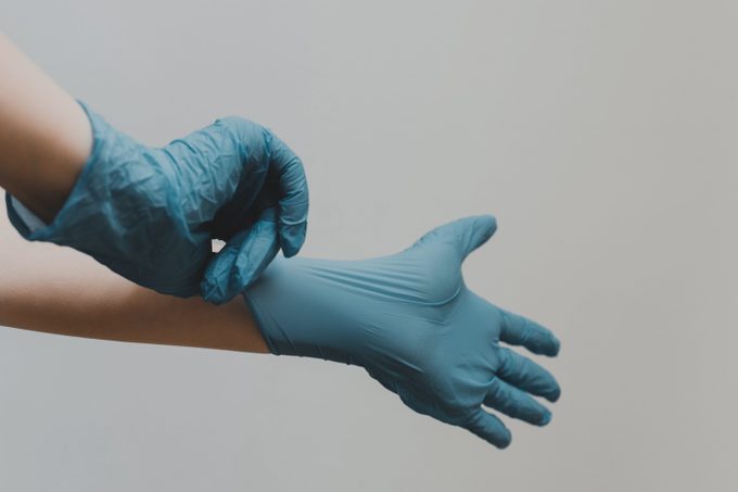 person putting on blue latex medical gloves
