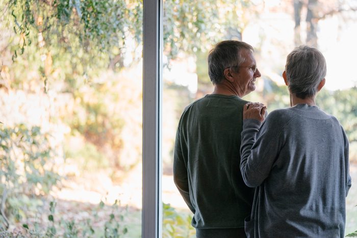 senior couple standing at window in home
