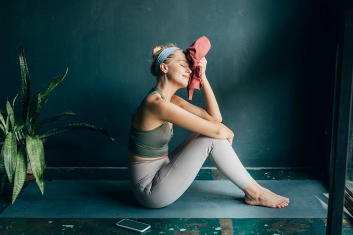 young woman tired from workout sitting on yoga mat