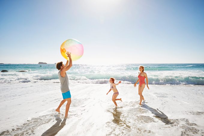 family playing with a beach ball on the beach