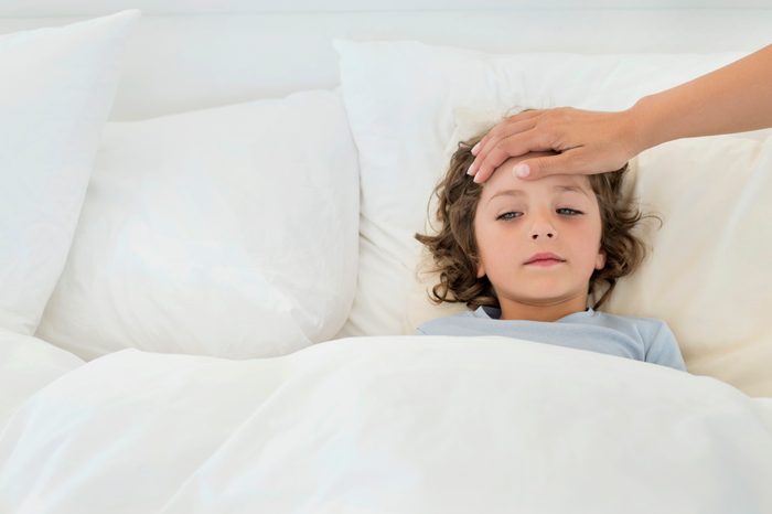 young boy sick in bed with fever