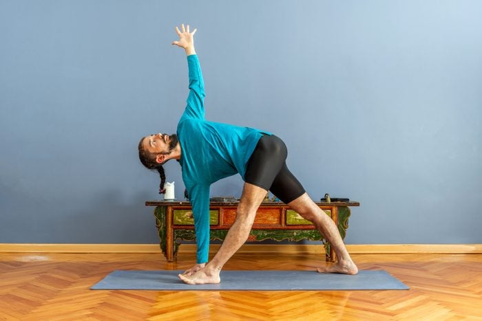 man doing revolved triangle yoga pose