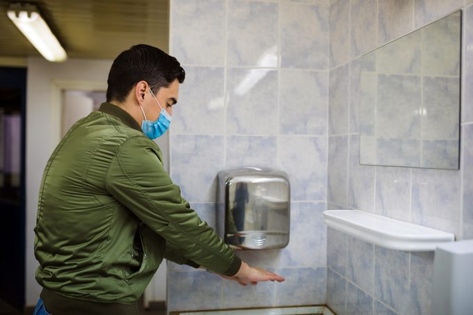 man drying hands in public restroom