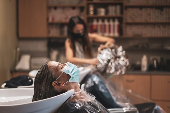 woman sitting at hair sink in salon during covid-19