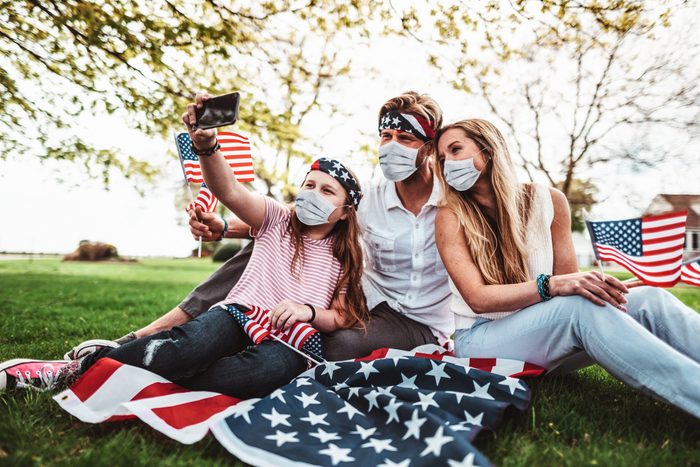 family celebrating fourth of july with face masks on to protect against coronavirus