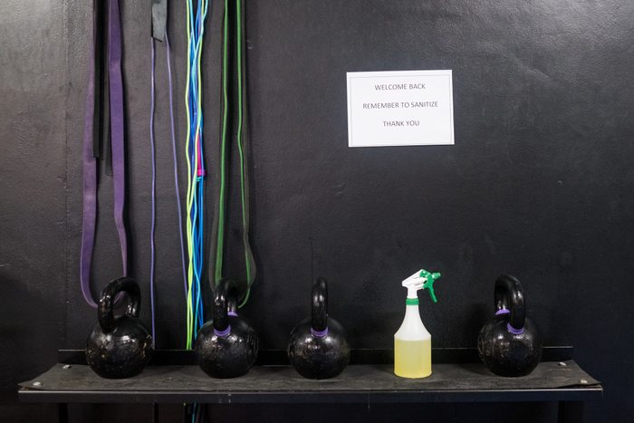gym weights and disinfectant under sign about keeping the gym clean during coronavirus