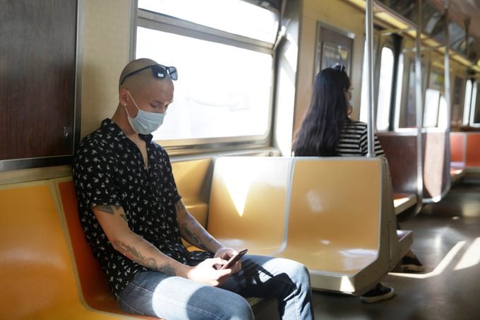 two people sitting on the subway with face masks on
