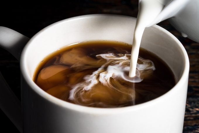 close up of milk being poured into a cup of coffee